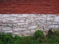 Détail du mur pignon sur rue : le soubassement en moellon de calcaire carbonifère (badigeonné de chaux).